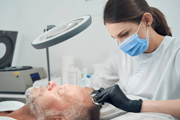 Esthéticienne en masque médical faisant injection dans la tête de l'homme — Photo