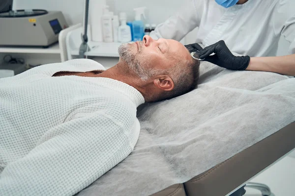 Uomo che riceve un trattamento di perdita di capelli in clinica cosmetologica — Foto Stock