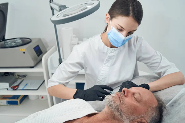 Man som får injektion på kinden på kosmetologiska kliniken — Stockfoto