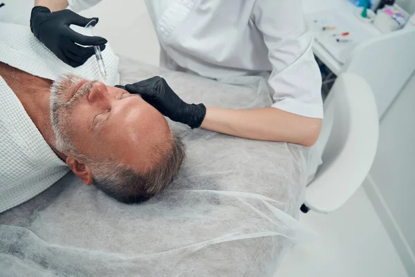 Мужчине делают укол лица в косметологической клинике — стоковое фото