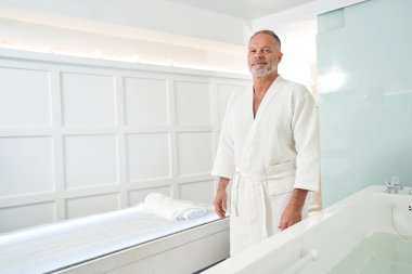 Masaj masasının yanında duran bir adam.