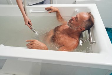 Sağlık merkezinde hidromasaj yaptıran bir adam.