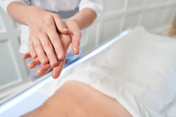 Massaggiatrice sfregamento mani con olio da massaggio nel salone spa — Foto Stock