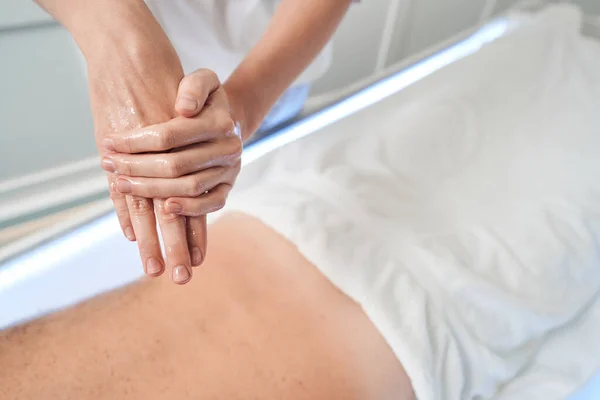 Massaggiatrice sfregamento mani con olio da massaggio prima della procedura — Foto Stock
