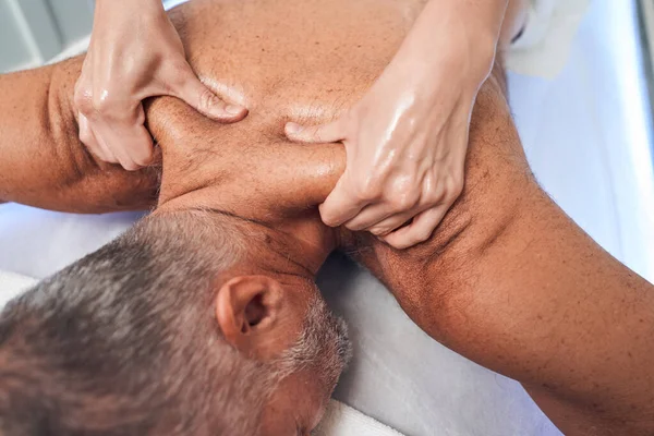 Mãos massagistas massageando ombros masculinos no salão de spa — Fotografia de Stock