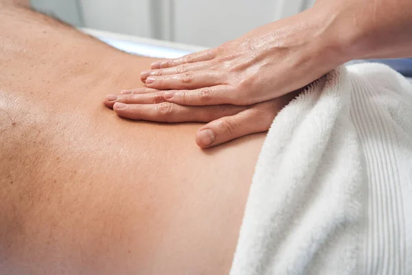 Massaggiatrice mani massaggiando maschio indietro nel salone spa — Foto Stock