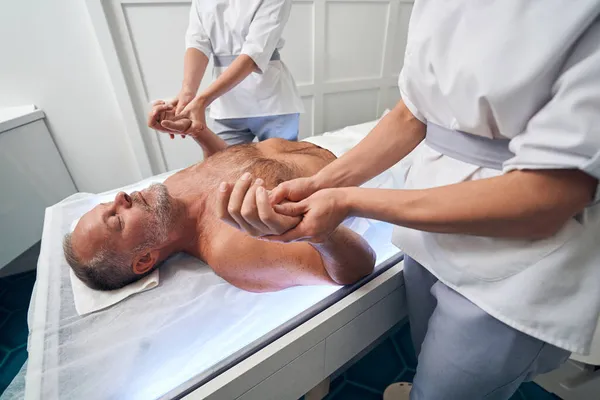 Мужчина получает профессиональный массаж рук в спа-салоне — стоковое фото