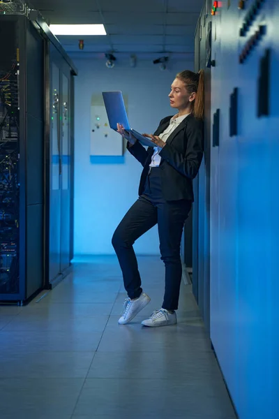 Técnico que utiliza el ordenador portátil en la sala de servidores del centro de datos — Foto de Stock