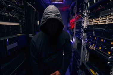 Karanlık sunucu odasında duran erkek hacker