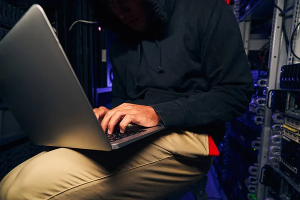 Hacker mengetik di laptopnya di ruang server gelap — Stok Foto