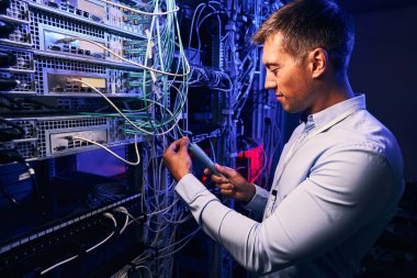 Odaklanmış veri merkezi çalışanı kablo altyapısını kontrol ediyor