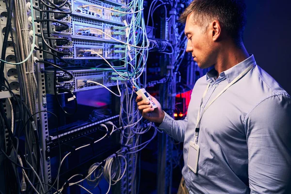 Ingeniero enfocado rastreando fallas en cables de red — Foto de Stock