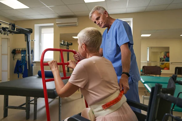 Mujer caucásica haciendo ejercicio con el cuidador en el centro de rehabilitación —  Fotos de Stock