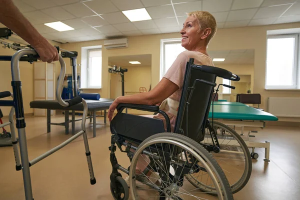 Physiotherapist assisting female patient in using walker at clinic — Stock Photo, Image