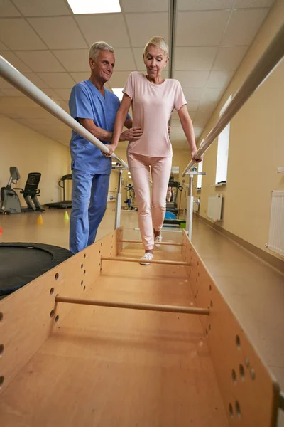 Profesyonel fizyoterapist rehabilitasyon merkezinde olgun bir kadınla çalışıyor. — Stok fotoğraf