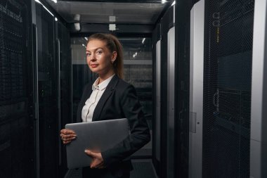 Veri merkezinde dizüstü bilgisayarı olan kendine güvenen bir iş kadını