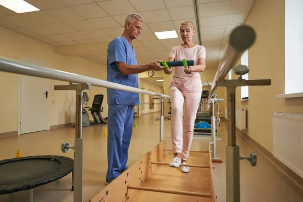 Fisioterapeuta con paciente con ictus durante el entrenamiento de equilibrio en el centro médico — Foto de Stock