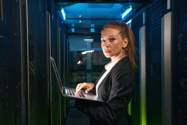 Entschlossene Frau mit Laptop arbeitet mit Servern im Rechenzentrum — Stockfoto