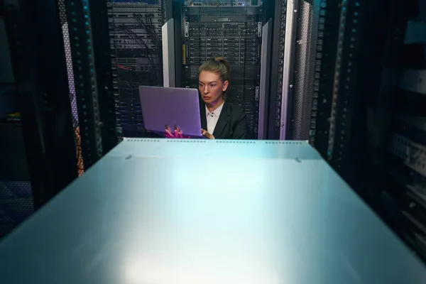 Netzwerktechnikerin benutzt Laptop, während sie im Serverraum arbeitet — Stockfoto