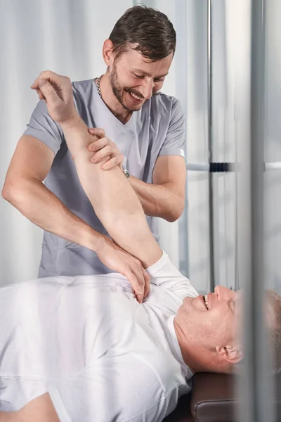 Quiroprático verifica músculos do braço, articulações do paciente na cama de massagem — Fotografia de Stock