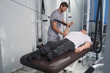 Rehabilitasyon merkezindeki masaj masasında hastanın kemerini çek.