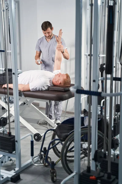 Kinetischer Therapeut behandelt männlichen Patienten auf Massagetisch in Reha-Klinik — Stockfoto