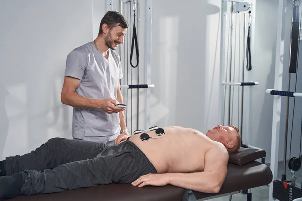 Spezialist setzt Elektrostimulator auf Magen von Mann mit Behinderung — Stockfoto