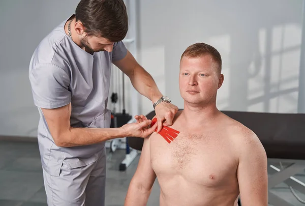 Therapeutische Behandlung der Schulterverletzung mit Kinesiotape durch den Therapeuten — Stockfoto