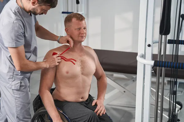 Therapeut legte Kinesiotape auf verletzten Brustmuskel von Rollstuhlfahrer — Stockfoto
