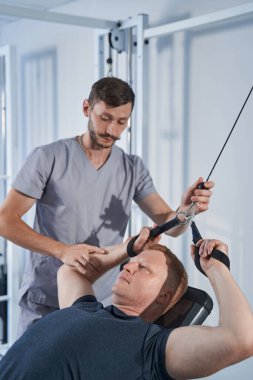 Özürlü genç adam, güç makinesine direnç bandı tak.