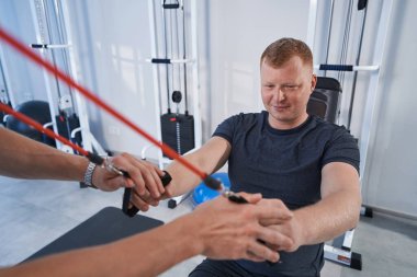 Hasta adam fizyoterapi kliniğinde burkulma simülatörüyle egzersiz yapıyor.