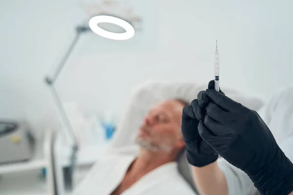 Beautician in gloves preparing syringe for procedure — Stock Photo, Image