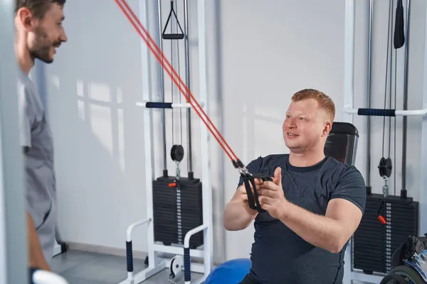 Patiënt trekt weerstandsbanden op krachttrainingsmachine — Stockfoto