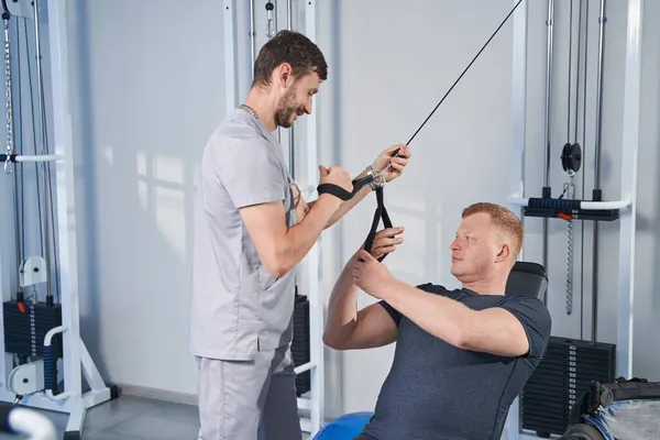 Terapia di riabilitazione dell'uomo con cinghie di trazione per disabilità sulla macchina da stretching — Foto Stock