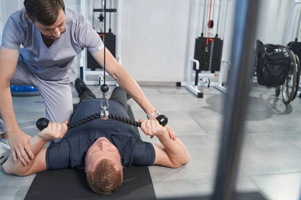 Patient with disability exercising on tether machine with therapist — Stock Photo, Image