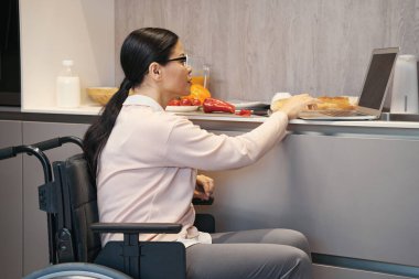 Mutfakta defter kullanan engelli bir kadın.