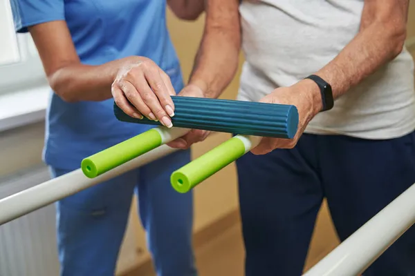 Healthcare professional helping mature patient exercising in hospital — Stock Photo, Image