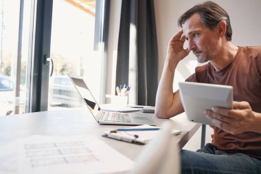 Ciddi yaşlı adam ofiste hesaplamalar yapıyor.