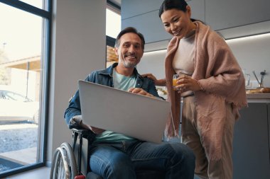 Mutfakta dizüstü bilgisayarda video izleyen neşeli çift.