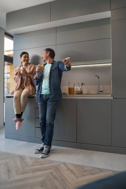 Mutlu, olgun bir çift mutfakta içki içiyor.