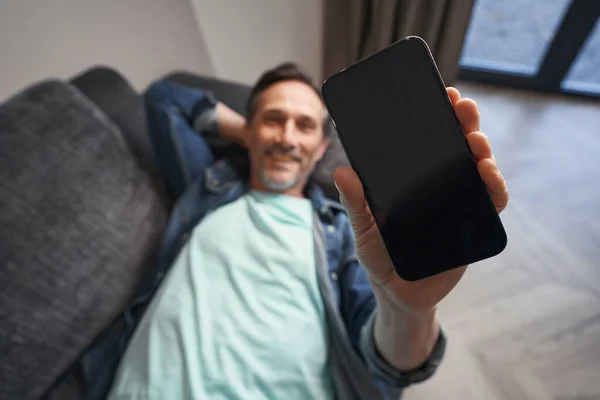 Χαμογελώντας άνθρωπος ξοδεύει χρόνο με το smartphone στο σπίτι — Φωτογραφία Αρχείου