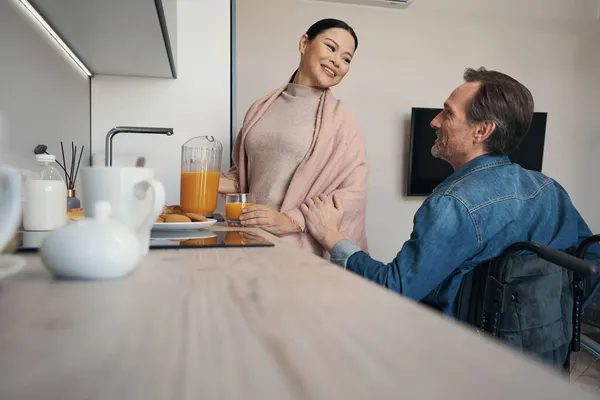 Glimlachende vrouw communiceren met man met een handicap in de keuken — Stockfoto