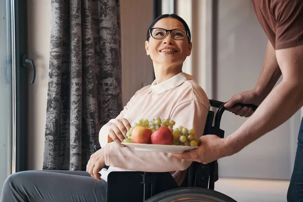 Ευτυχισμένη γυναίκα με αναπηρία να πάρει φρούτα από το στοργικό σύζυγο — Φωτογραφία Αρχείου