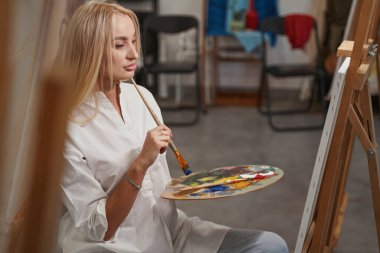 Resmine bakan düşünceli genç bir kadın.