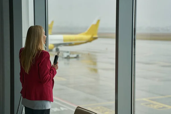 공항 터미널 창문 근처의 여성, 활주로를 바라보고 있습니다. — 스톡 사진