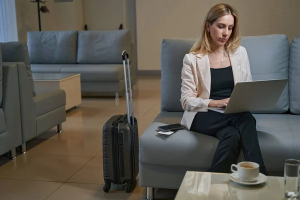 Female traveler working on laptop sitting on sofa in hotel — Stock Photo, Image