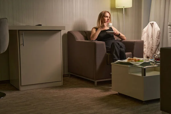 Женщина отдыхает в гостиничном кресле с чашкой кофе — стоковое фото