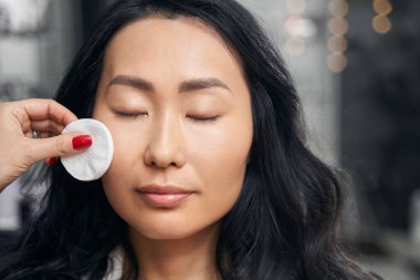 Çekici bir kadın, makyajcı eli süngerli.