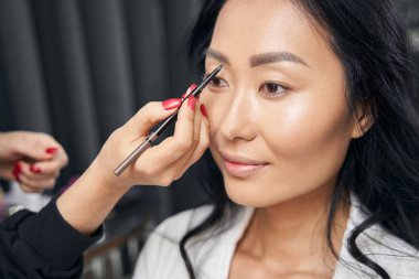 Genç zarif iş kadını güzellik alanında profesyonel makyaj yaptırıyor.