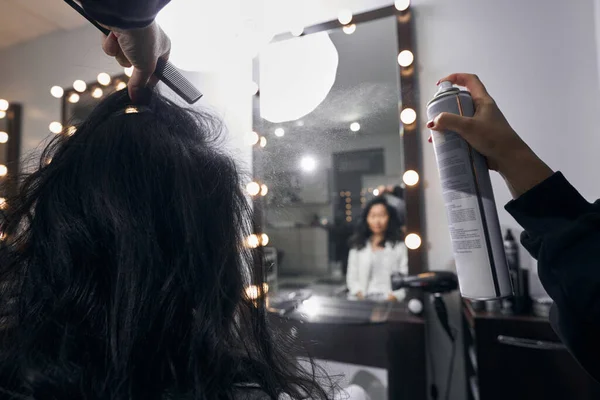 Kuaför kuaförde saç spreyi kullanıyor.